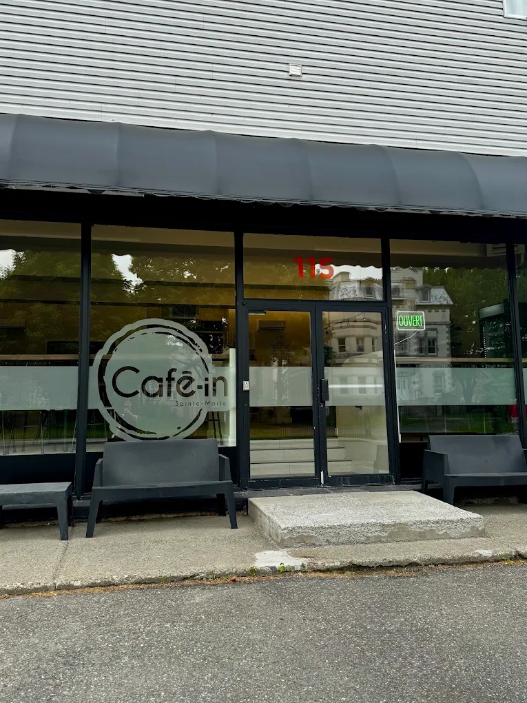 La devanture du Café-in de jour : logo sur la vitrine, numéro 115 au-dessus de la porte et enseigne Ouvert
